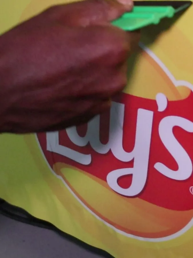 Squeegee smoothing vinyl over the Lays logo