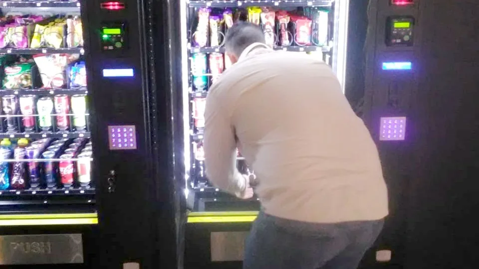 Operator restocking an open snack and drinks vending machine