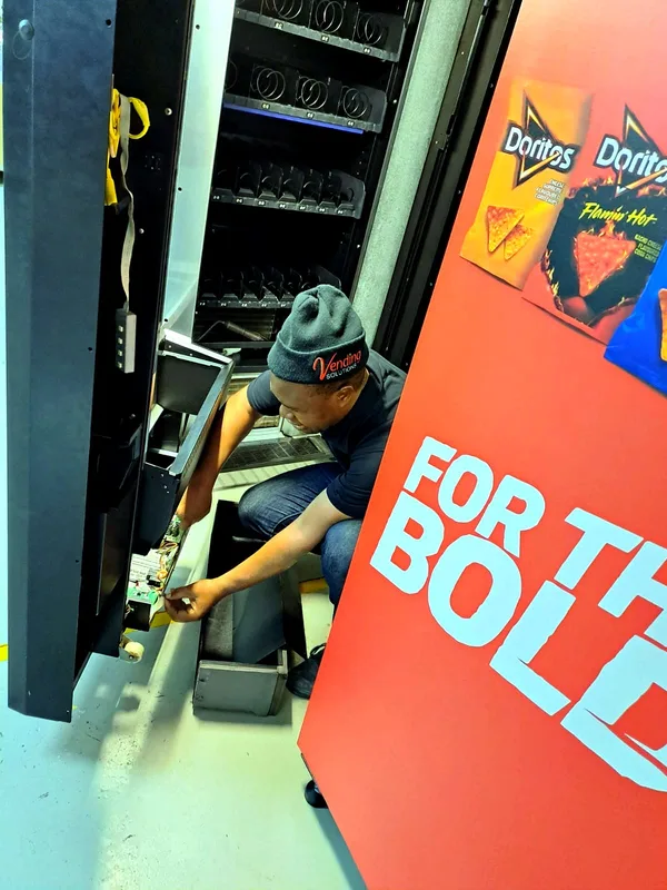 Technician working inside an open snack machine